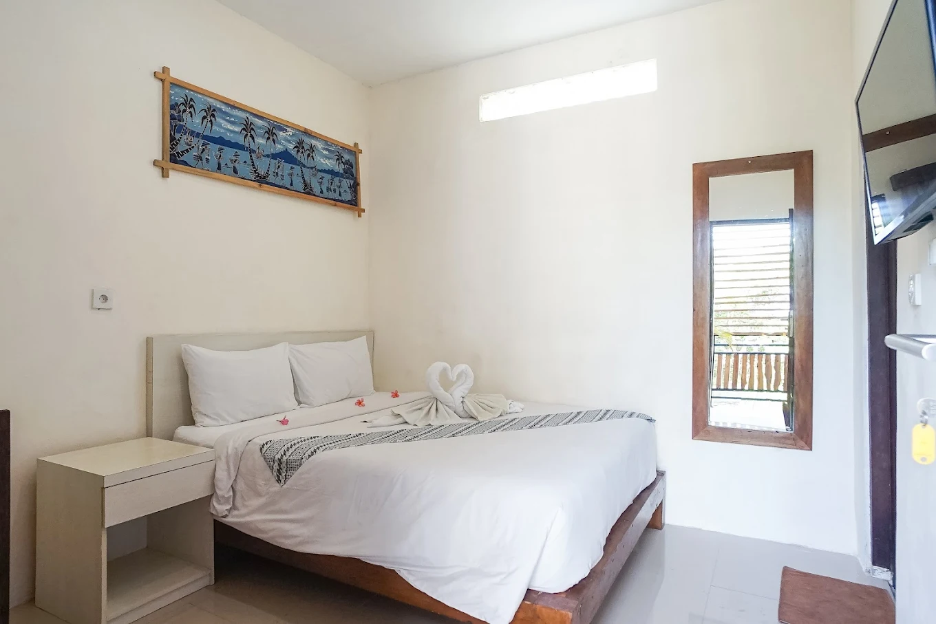 Pudi Homestay deluxe room with comfortable bed and Balinese artwork